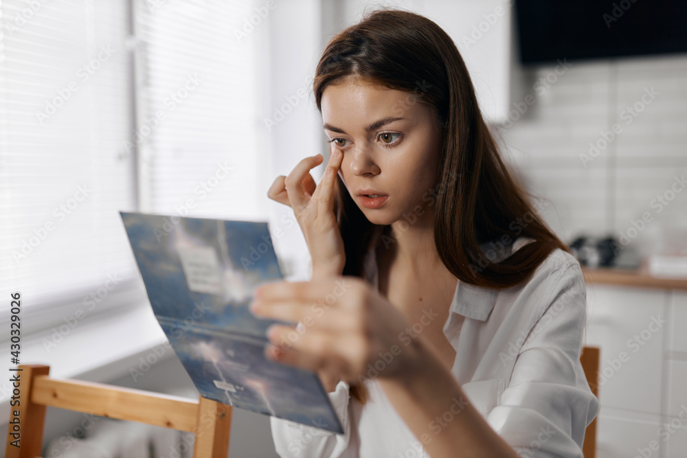 beautiful woman with makeup brush at the table in the kitchen and mirrored hand beautiful woman with makeup brush at the table in the kitchen and mirrored hand