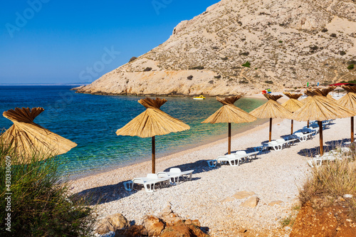 Straw umbrellas in the beautiful Oprna beach in the Krk island