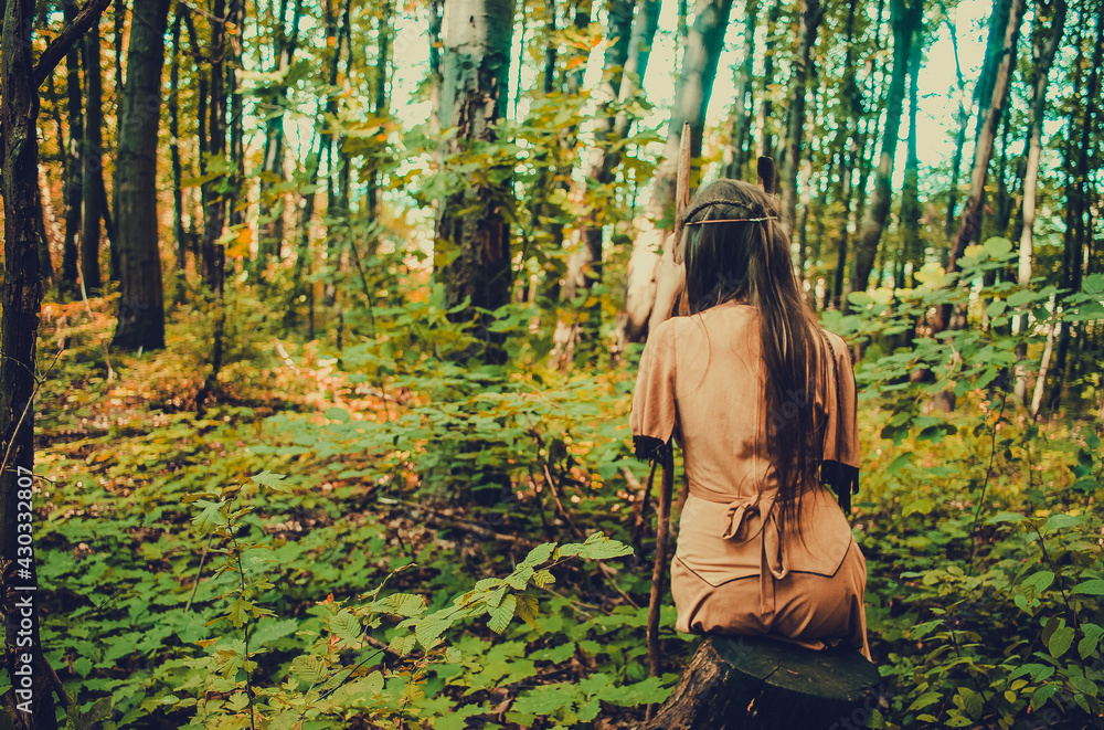 Beautiful woman in traditional tribal dress meditating in the woods, native american indian shaman meditating outdoors, natural medicine concept Beautiful woman in traditional tribal dress meditating in the woods, native american indian shaman meditating outdoors, natural medicine concept