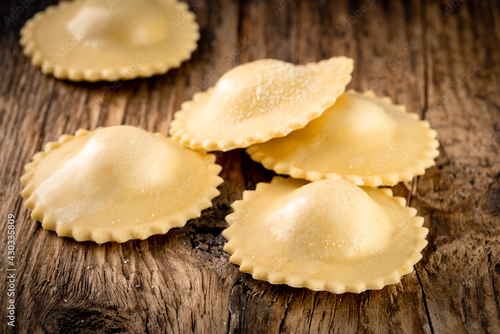 Round classic ravioli with filling on a wooden background. Fresh Italian pasta ravioli, rustic style Round classic ravioli with filling on a wooden background. Fresh Italian pasta ravioli, rustic style
