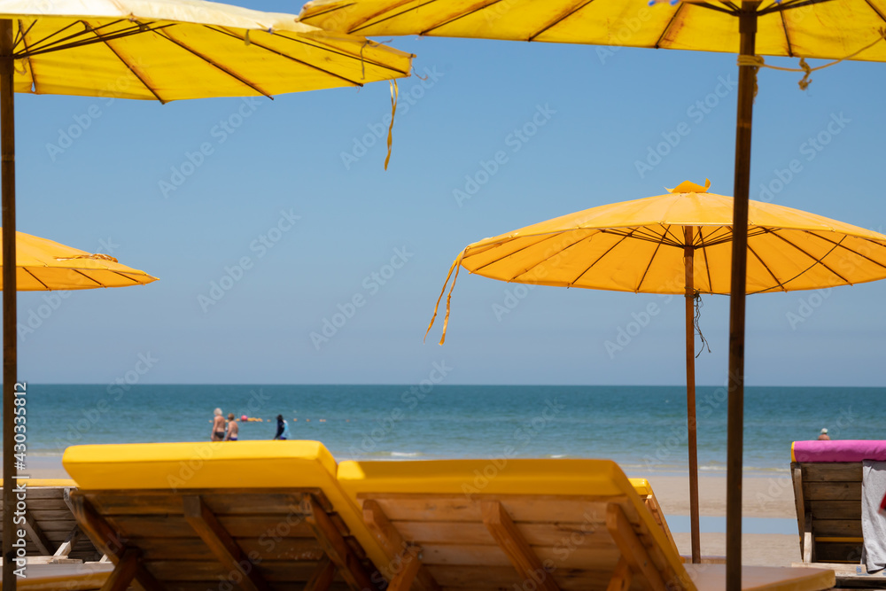 yellow beach umbrella with wooden bench as foreground. concept : travel sea in summer time.