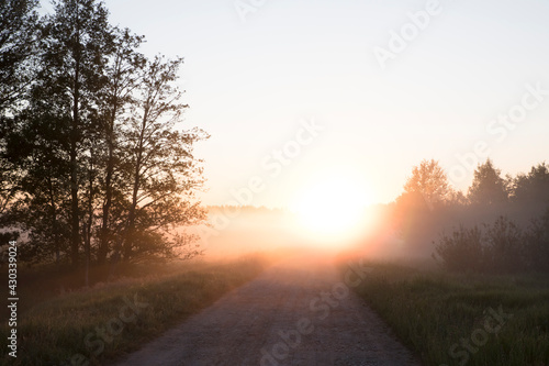 Scenic view to the country road with the fog clad sunrise 