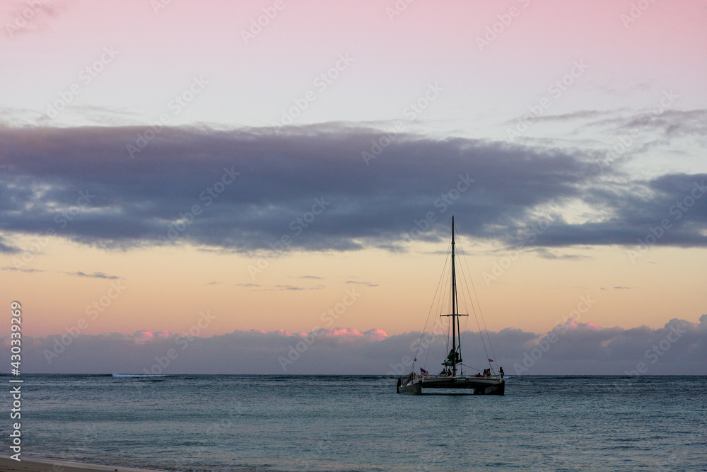 A boat sails into the sunset on Waikiki Beach, Hawaii