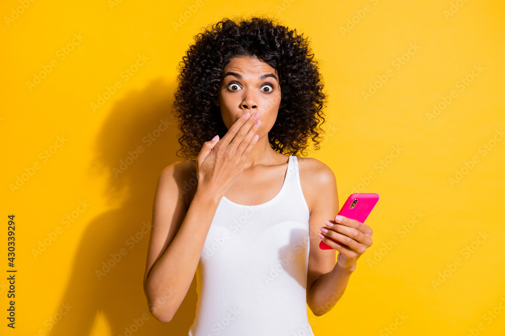Portrait of worried dark skin lady arm palm covering mouth staring camera isolated on yellow color background Portrait of worried dark skin lady arm palm covering mouth staring camera isolated on yellow color background
