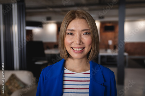 Portrait of happy asian businesswoman standing in an office room smiling