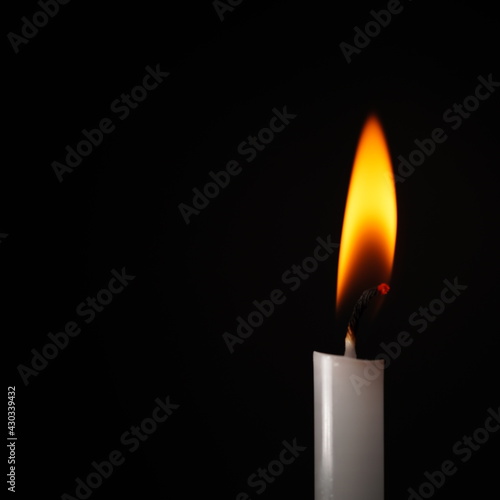 White candle flame isolated on black background religious concept belief and peace.