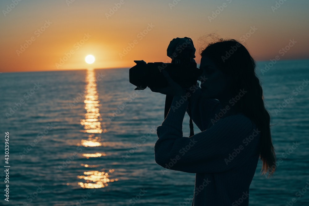 woman photographer with camera at sunset near the sea nature landscape