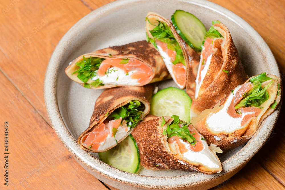Stack of pancakes with salted salmon and cream cheese Philadelphia in a bowl. Over rustic wooden background.