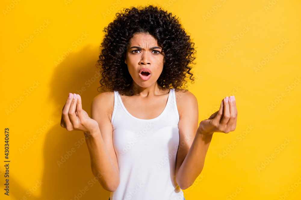 Portrait of unsatisfied dark skin lady open mouth arms fingers show money symbol isolated on yellow color background Portrait of unsatisfied dark skin lady open mouth arms fingers show money symbol isolated on yellow color background