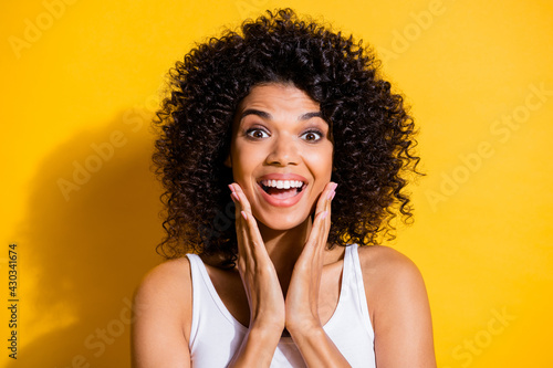 Photo of cheerful astonished dark skin lady arms on cheeks open mouth isolated on yellow color background
