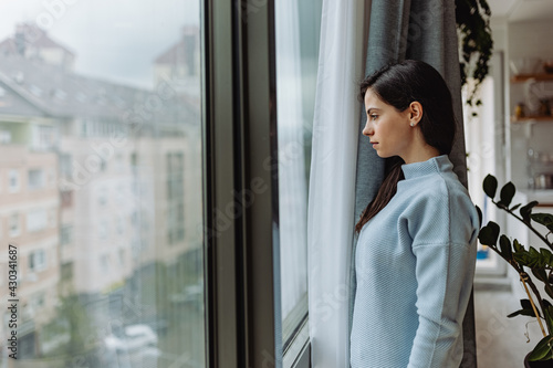 Young woman enjoying indoor, while watching rain through the window.