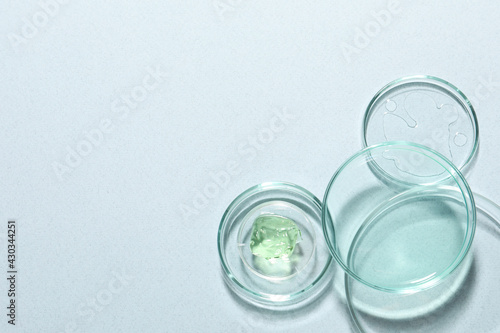 Organic cosmetic product and laboratory glassware on light background, flat lay. Space for text