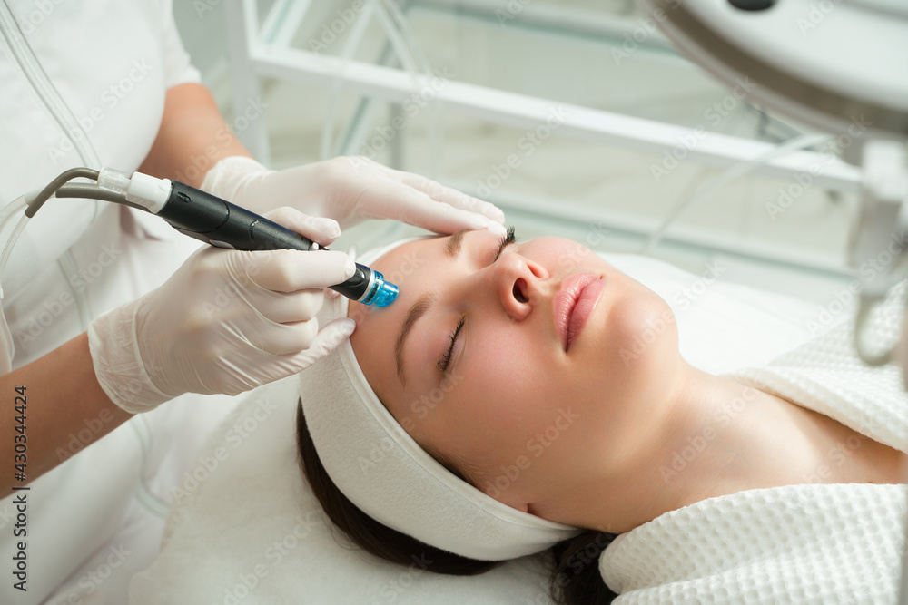 Naklejka premium A woman receives laser treatment of the face in a cosmetology clinic, a concept of skin rejuvenation is being developed. laser peeling