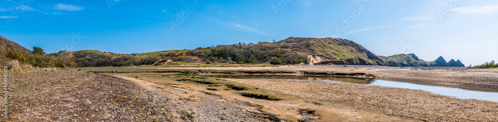 A panorama view across the stream and the beach at Three Cliffs Bay, Gower Peninsula, Swansea, South Wales on a sunny day A panorama view across the stream and the beach at Three Cliffs Bay, Gower Peninsula, Swansea, South Wales on a sunny day