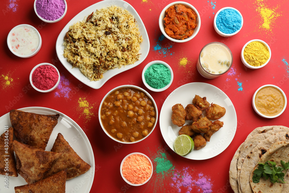 Traditional Indian food and color powder dyes on red background, flat lay. Holi festival Traditional Indian food and color powder dyes on red background, flat lay. Holi festival