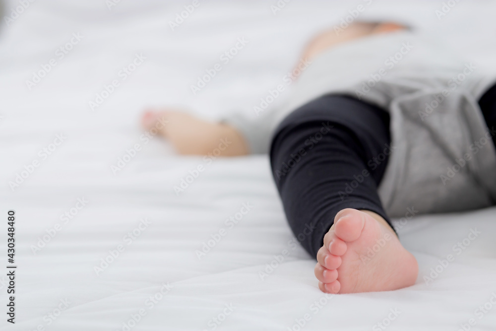 Fototapeta premium Closeup foot of asian little baby girl sleeping on bed in the bedroom at home, newborn napping with cozy and relax, infant innocence in bedtime, happy toddler cute, growth of child and emotion.