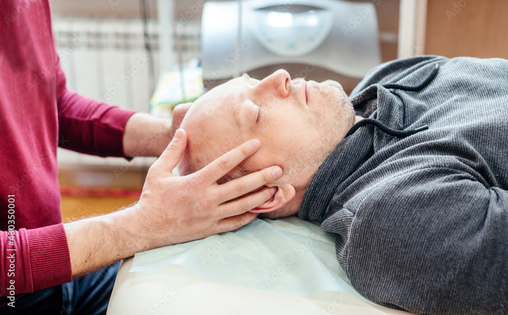 Male Patient Receiving Cranial Sacral Therapy Lying On The Massage Table In Cst Osteopathic