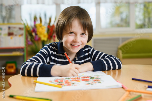 Smiling preschool boy draws in his notebook