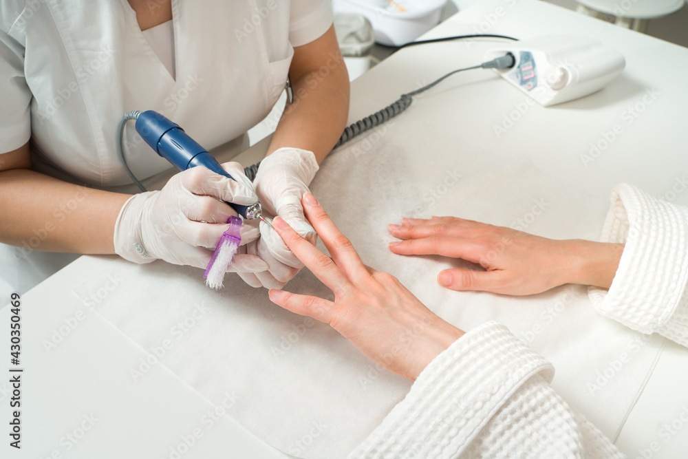 Woman in a nail salon receiving a manicure by a beautician with nail file. Beauty and hand care close-up. Woman in a nail salon receiving a manicure by a beautician with nail file. Beauty and hand care close-up.