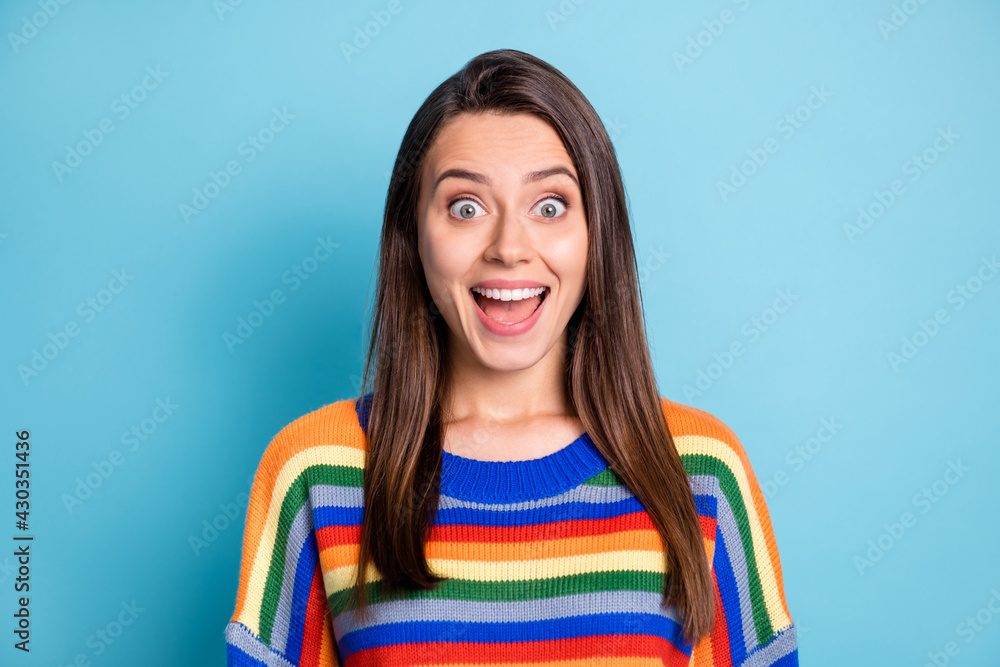 Photo portrait of amazed surprised girl smiling in striped sweater isolated on vivid blue color background Photo portrait of amazed surprised girl smiling in striped sweater isolated on vivid blue color background