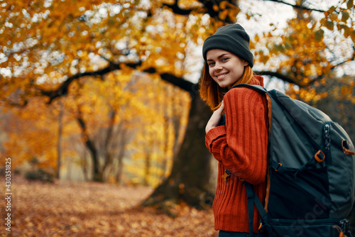 happy woman with backpack walking in park in nature in autumn cropped view