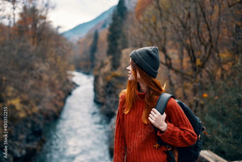 woman with backpack admires the river in the mountains nature