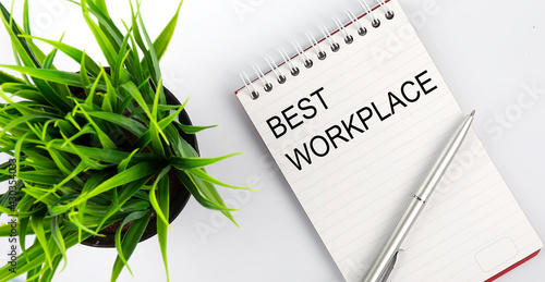 Keyword BEST WORKPLACE - business concept text on a white notebook and pen, green flowers