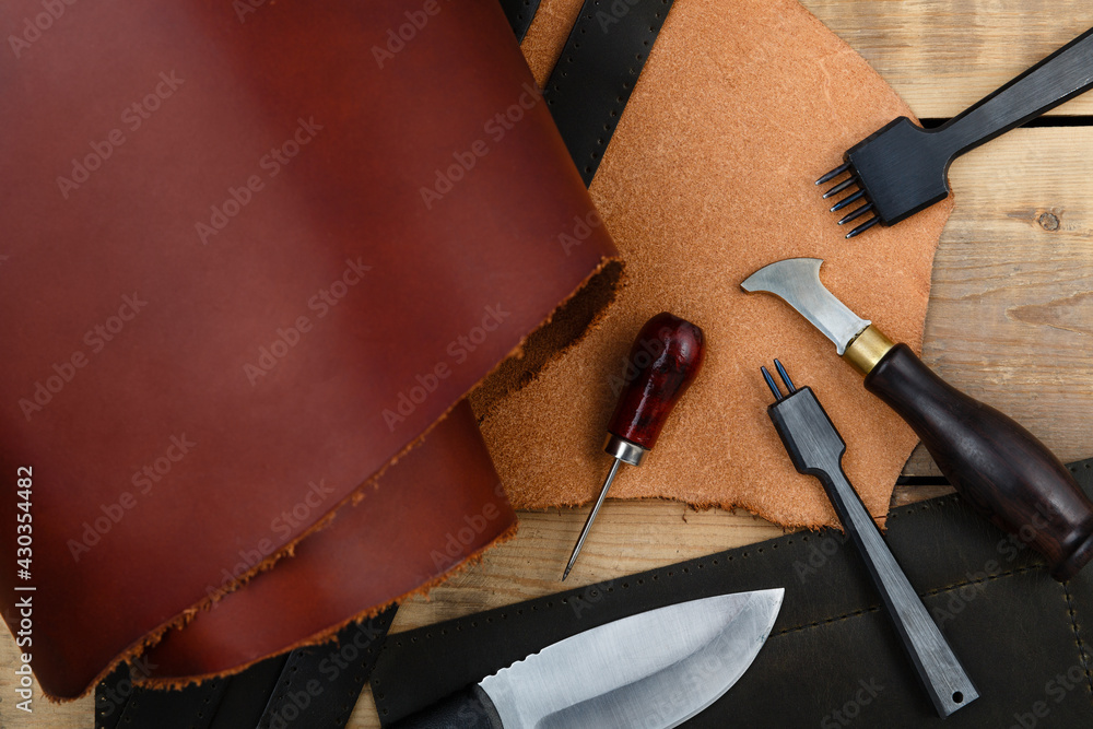 Naklejka premium Leatherworker's tools on a wooden workbench.