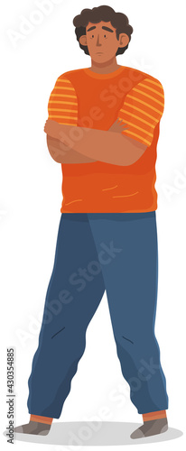 Young unhappy man with black hair dressed in casual clothes. Male sad character standing isolated on white background wearing jeans and t-shirt, hands folded in displeasure, disconcerted guy