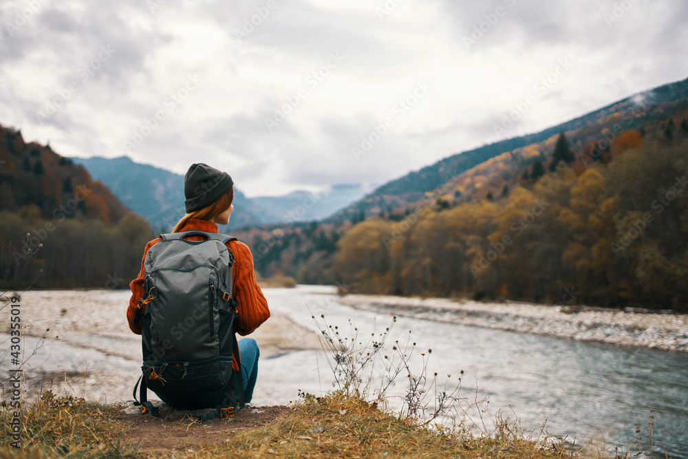 a traveler in a jacket with a backpack on her back hat mountains landscape river a traveler in a jacket with a backpack on her back hat mountains landscape river
