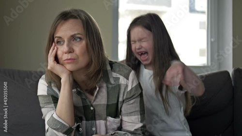 Tired woman cannot respond to the outcry of a child. The child wants to get the mother's attention.
