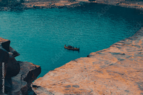 Eerie scenery of people on an old wooden shallop on the blue waters of a lake