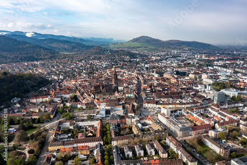 Luftaufnahme von Freiburg im Breisgau, das Münster mit speziellem gotischem turm im Vordergrund und schneebedeckte Berge im Hintergrund, Baden Wuertenberg, Deutschland