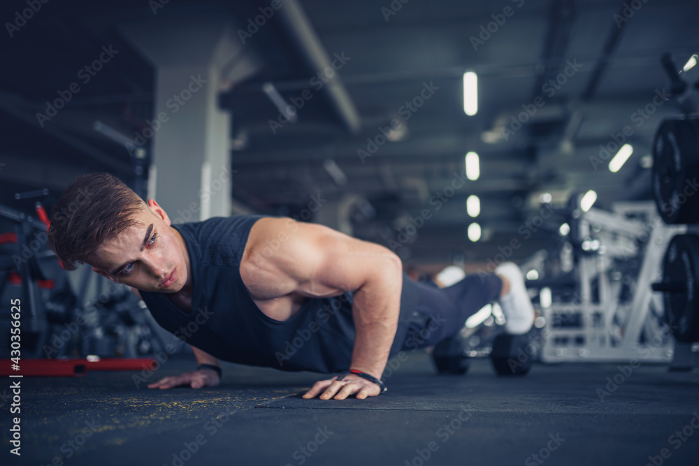 Fototapeta premium Young athletic man doing push-ups in gym. Muscular and strong gu