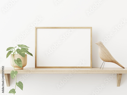 Small horizontal wooden frame mockup in scandi style interior with trailing green plant in pot, bird and shelf on empty neutral white wall background. A4, A3 format. 3d rendering, illustration