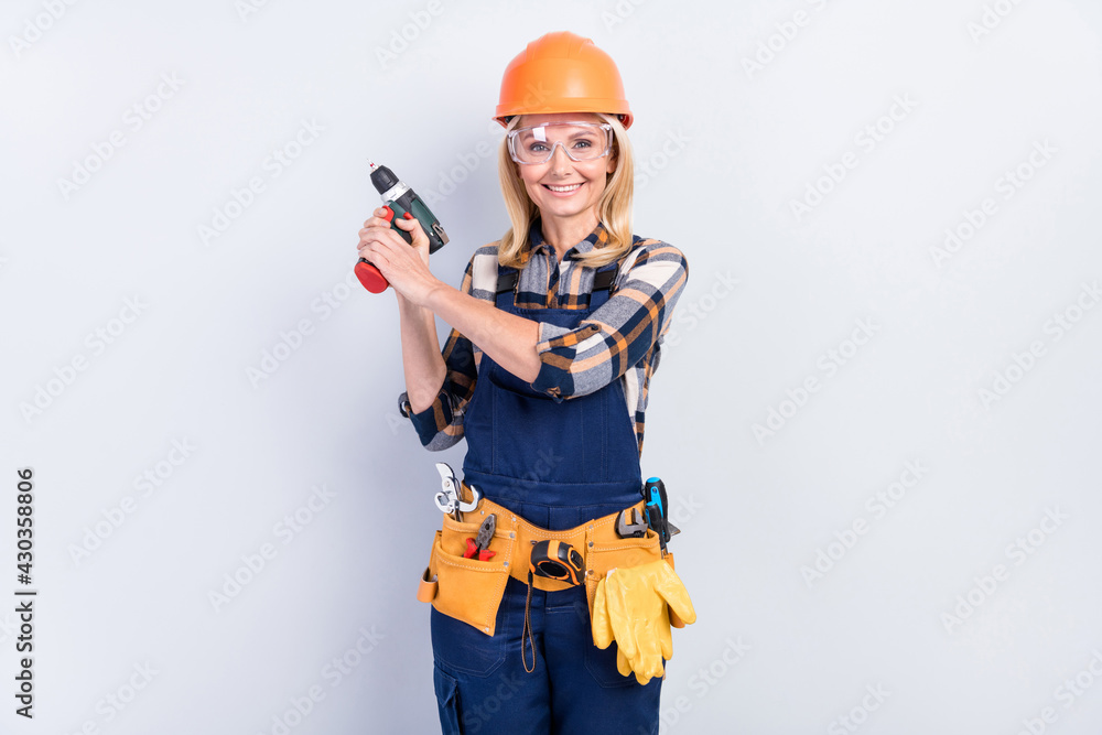 Photo of cheerful pretty age crafts lady dressed blue uniform smiling holding screwdriver isolated grey color background