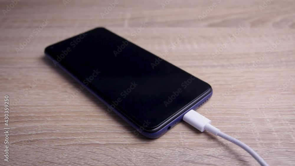 A person connects the charger to the phone in close-up. Connecting power to a low-power smartphone. The person charges the phone. A person connects the charger to the phone in close-up. Connecting power to a low-power smartphone. The person charges the phone.