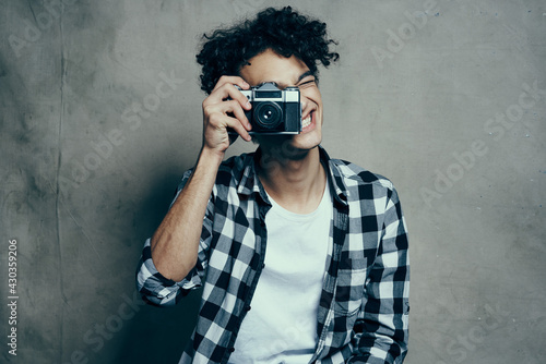 guy with a camera in his hands on a gray background indoors hobby plaid shirt model