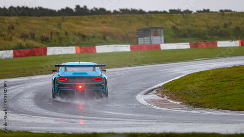 A panning shot of a racing car as it circuits a track.