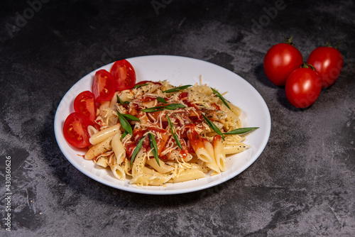 Penne pasta with tomatoes, sauce, cheese and Provencal herbs. Dark background. Space for copying. Top view. Penne pasta in tomato sauce - Italian food style photo