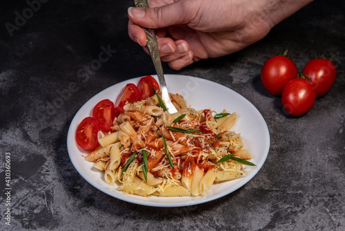 Penne pasta with tomatoes, sauce, cheese and Provencal herbs. Dark background. Space for copying. Top view. Penne pasta in tomato sauce - Italian food style photo