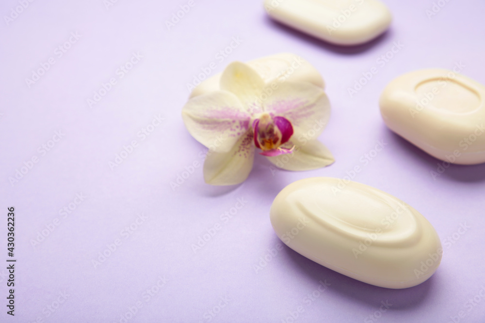 Different white soaps with flowers. A lot of solid soap for hygiene and cleanliness on purple background.