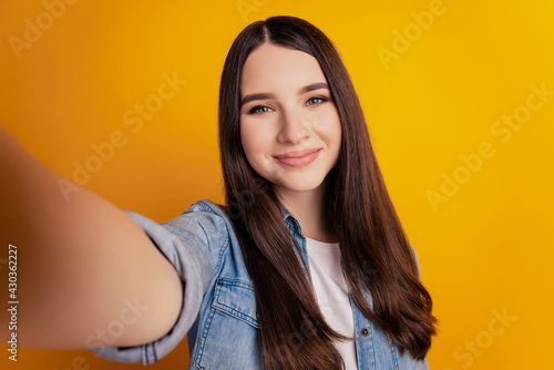 Close-up of young beautiful woman taking selfie on yellow wall