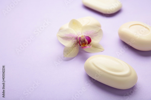 Different white soaps with flowers. A lot of solid soap for hygiene and cleanliness on purple background.