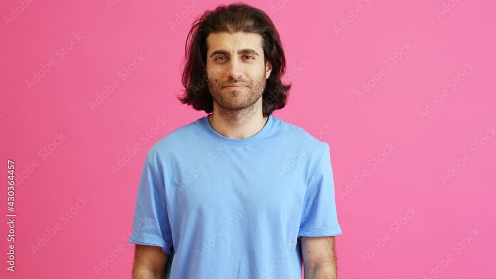 A man with long hair saying yes positively shaking his head while standing in a pink studio A man with long hair saying yes positively shaking his head while standing in a pink studio