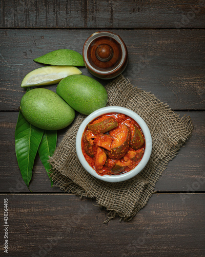natural and homemade mango pickle or aam ka aachar on a rustic wooden background theme 