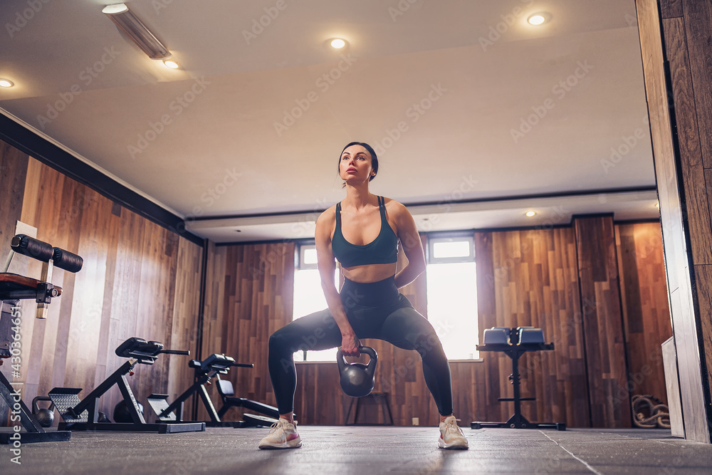Young adult fitness woman doing swing exercise with a kettlebell