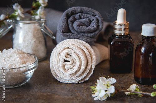 Beauty spa treatment and relax concept. Towel, sea salt and essential oils on a dark background