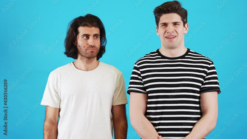 A surprised men not knowing what to do looking around and shrugging shoulders in a blue studio A surprised men not knowing what to do looking around and shrugging shoulders in a blue studio