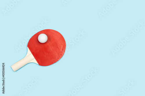 Raqueta de ping-pong con una pelota sobre un fondo celeste liso y aislado. Vista superior. Copy space. Concepto: Deportes photo